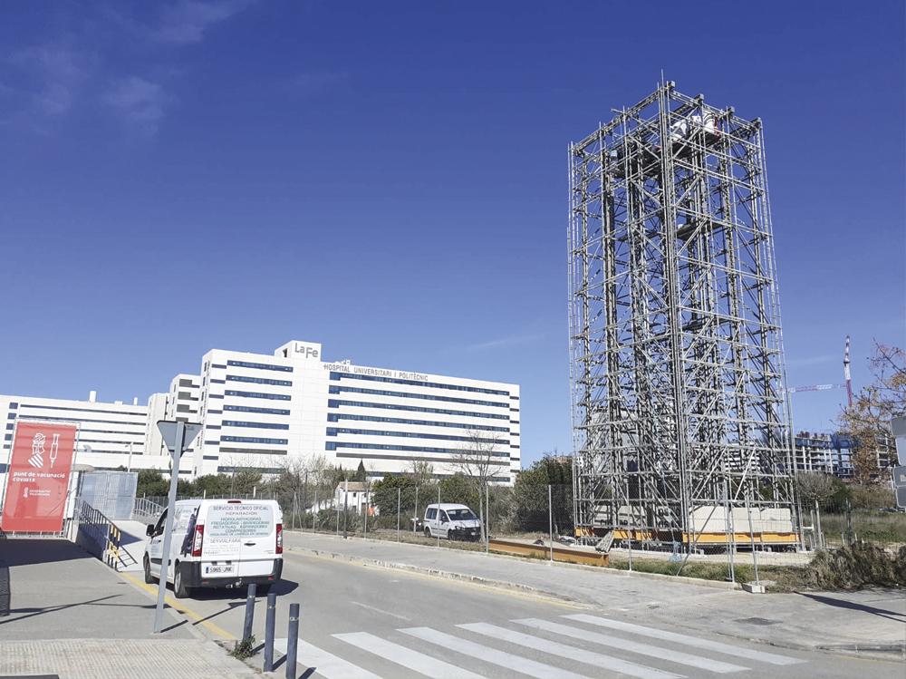 Calzada con aceras y un andamio en la parte derecha. Al fondo el edificio del hospital La Fe de Valencia.