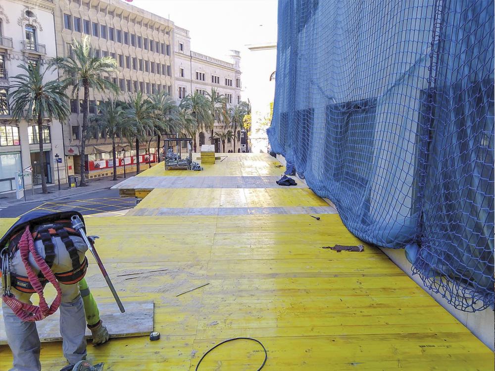 Primer plano de plataforma de madera en la parte inferior de edificio, con red de seguridad.